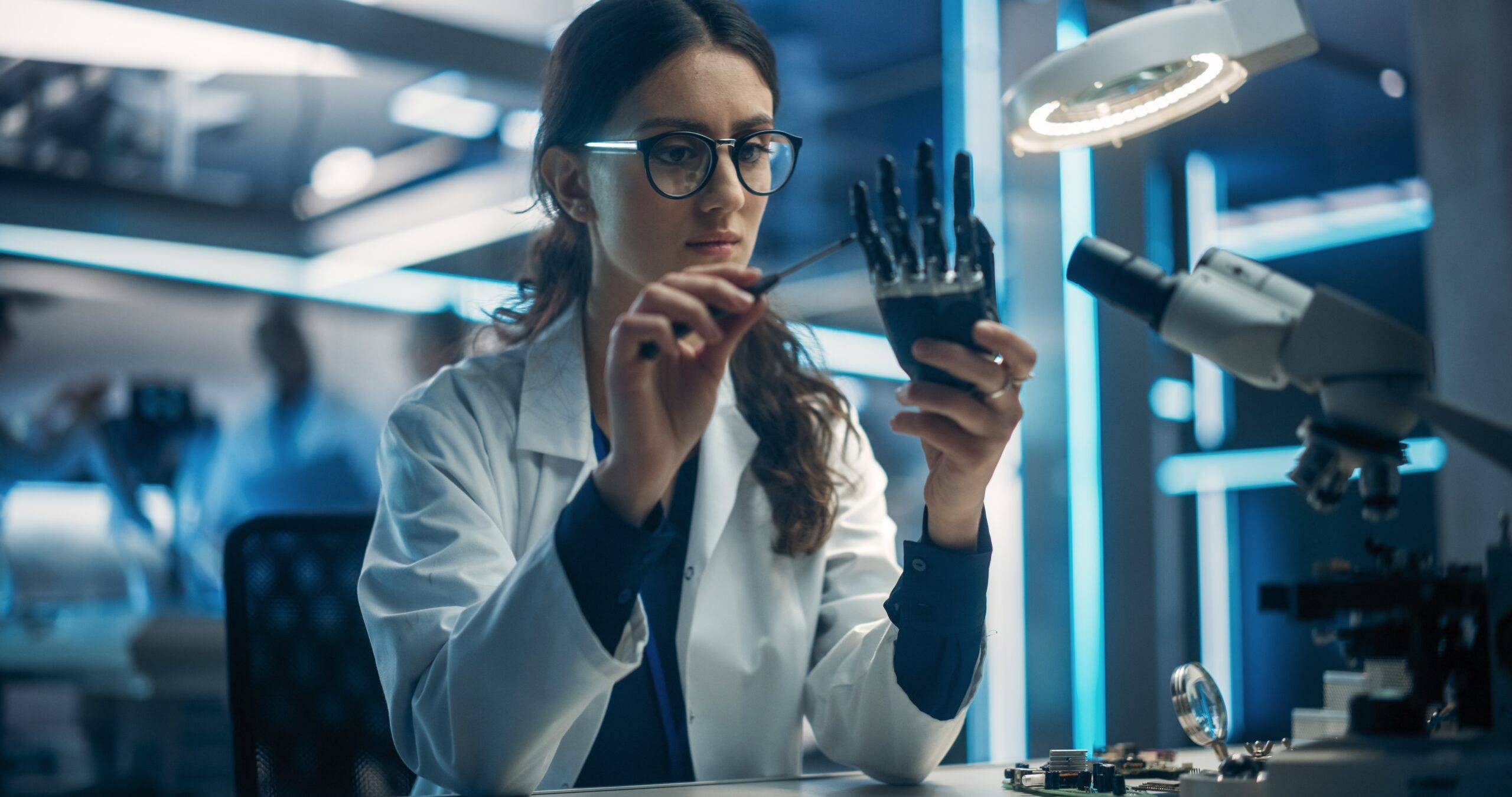 Stock image of a young scientist working in technological research and development company, assembling an  innovative bionic prosthetic hand for the physically impaired.